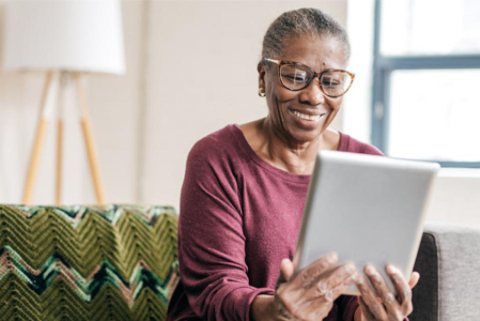 Image of an African American woman looking at a tablet and smiling