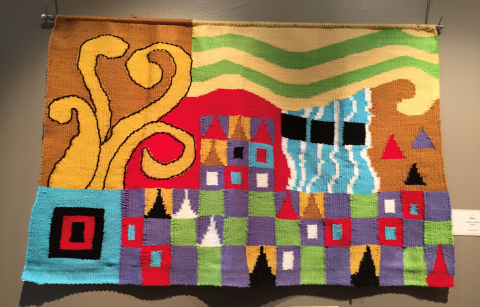 Photo of a tapestry featuring many bright colors and various shapes. 