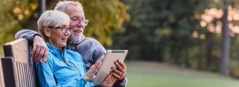 Male-presenting and female-presenting individuals looking at tablet device