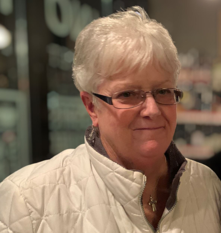 Retiree Carol Conway in a photo. She is wearing a white jacket and reading glasses.