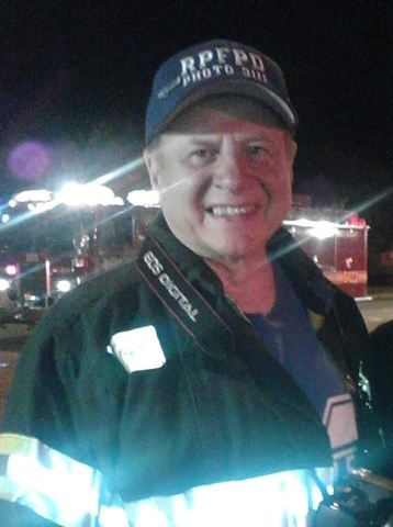 Retiree Don Fontana in his Fire Service uniform. It is nighttime, he is wearing a cap, he is smiling.